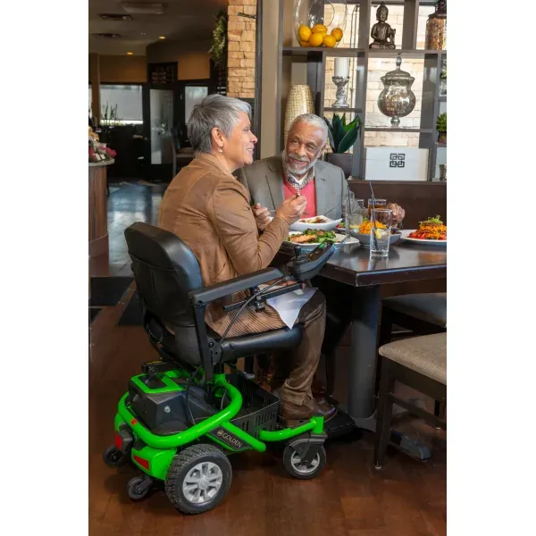 Envy electric wheelchair user dining at a restaurant, demonstrating powered mobility for social outings.